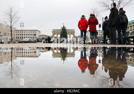 Berlin, Allemagne. 28 novembre 2017. Le monument de la capitale - la porte de Brandebourg - et les touristes reflétés par une flaque d'eau de pluie sur la place de Paris à Berlin, Allemagne, 28 novembre 2017. Crédit : Wolfgang Kumm/dpa/Alamy Live News Banque D'Images