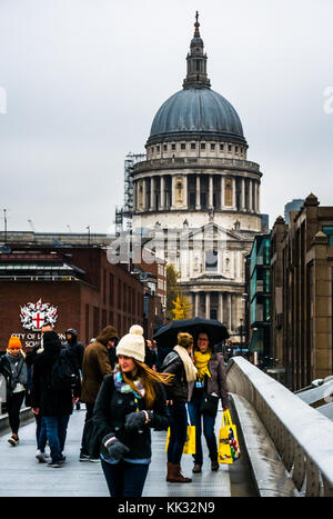 Les gens qui marchent sur le pont du millénaire sur jour de pluie à la Cathédrale St Paul et la City of London School, Thames, Angleterre, RU Banque D'Images