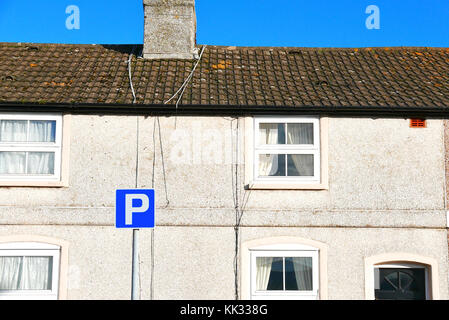 Rangée de petits cottages avec parking sign carré bleu à l'avant Banque D'Images