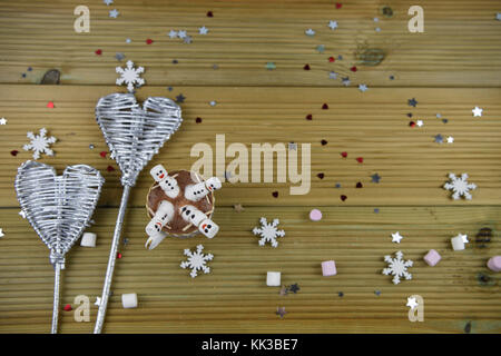 La saison d'hiver photographie image romantique avec du chocolat chaud verre rempli de mini guimauves avec sourires et argent glacé sur fond de formes coeur Banque D'Images