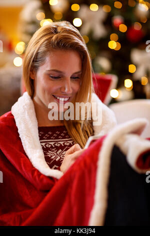 Beautiful smiling woman texting messages sur vacances de Noël Banque D'Images