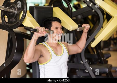 Jeune homme fort de l'exercice pour les muscles des bras à un club de remise en forme w Banque D'Images