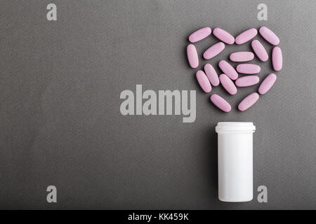 Comprimés versé d'un récipient en plastique d'un coeur, l'idée de traiter les maladies du cœur Banque D'Images