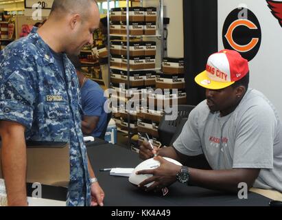 David Mims, Left Tackle for the Kansas City Chiefs, autographe un ballon de football pour le Chief Aviation Structural Mechanic Gilberto Espinosa lors d'une visite à la Norfolk Navy Exchange, Norfolk, Virginie, 2012. Image avec la permission du Matelot de 1re classe Lacordrick Wilson/US Navy. Banque D'Images