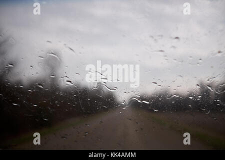 Perles de l'eau de pluie condensé sur une sous-fenêtre regardant à travers la vitre à l'extérieur de la scène floue avec des nuages gris Banque D'Images