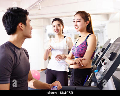 Hommes et femmes en pleine discussion dans une salle de sport tout en faisant une pause. Banque D'Images