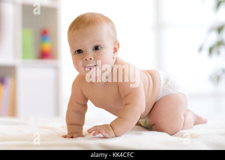 Portrait d'un bébé rampant sur le lit dans la chambre maternelle Banque D'Images