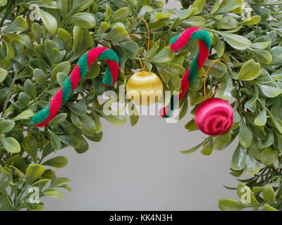 Couronne de Noël ou garland fait par feuille en plastique décorées en rouge et en canne blanche et jaune et rouge apple en close up isolé sur fond blanc Banque D'Images