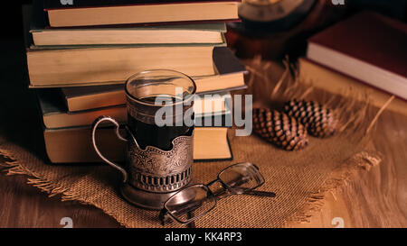 Livres anciens et de thé dans la soirée. Un verre de verre sur la table. Banque D'Images