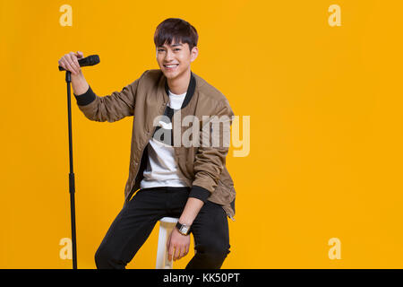 Cheerful young Chinese man singing with microphone Banque D'Images