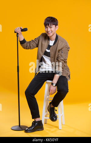 Cheerful young Chinese man singing with microphone Banque D'Images