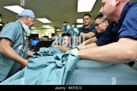 Des militaires de l'US Navy et de l'armée australienne aident à soulever une femme philippine sur un lit dans l'unité de soins intensifs à bord du navire-hôpital USNS Mercy T-AH 19 du Military Sealift Command lors du Pacific Partnership 2012, Samar, Philippines, 2012. Image reproduite avec l'aimable autorisation de Kristopher Radder/US Navy. Banque D'Images