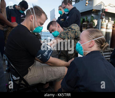 OCÉAN ATLANTIQUE (nov 22, 2017) le lieutenant Christopher Mullahey (au centre) de Baltimore et de l'hôpital Corpsman 2e classe Rachel Gutches de Central point, Oregon, prend des viaux d'une Marine agissant comme un évacuateur simulé lors d'un exercice d'évacuation non combattant à bord du navire d'atterrissage USS Oak Hill (LSD 51). Oak Hill, des composantes du Iwo Jima Amphiobie Ready Group et de la 26e unité expéditionnaire maritime, mène un exercice combiné d'unité de formation composite qui est le point culminant de la formation de l'équipe Marine-Marine corps et les certifiera pour le déploiement Banque D'Images