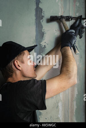 Marteaux homme un clou avec un pied dans un mur pour fixer la table dans l'avenir Banque D'Images