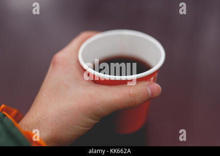 Photo de man's hand holding papier rouge avec plateau en verre sur fond violet floue Banque D'Images