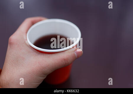 Photo de man's hand holding papier rouge avec plateau en verre sur fond violet floue Banque D'Images