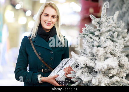 Image de la femme avec don dans la case d'arbre de Noël blanc en magasin. arrière-plan flou. Banque D'Images