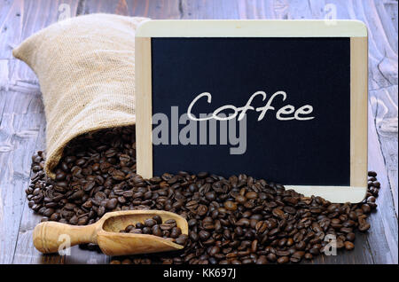 Café en grains avec tableau noir sur une table en bois. Banque D'Images