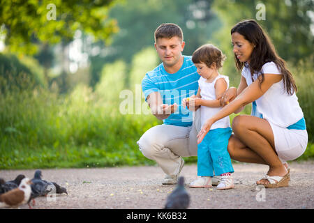 L'alimentation de la famille heureux pigeons dans parc d'été
