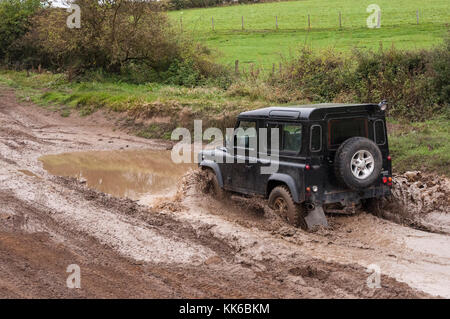 Un court-circuit en fonction de roue land rover le labour au moyen d'une eau boueuse à l'état humide la pulvérisation de l'eau octobre jour c'est tout. Banque D'Images