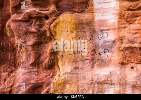 Close up de grès rose et orange minéral des modèles dans falaise, Petra, Jordanie, Moyen-Orient, avec l'Arabe de l'écriture Graffiti Banque D'Images