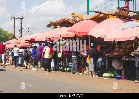 Une longue rangée de bordure, les étals de marché de fruits et légumes frais des personnes qui se promènent, Kenya, Afrique de l'Est Banque D'Images