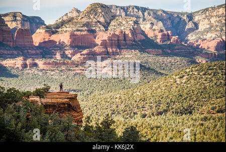 Une femme seule Randonneur au sommet d'un éperon rocheux dominant le Red Rock Canyon en dehors de Sedona, Arizona, USA. Banque D'Images