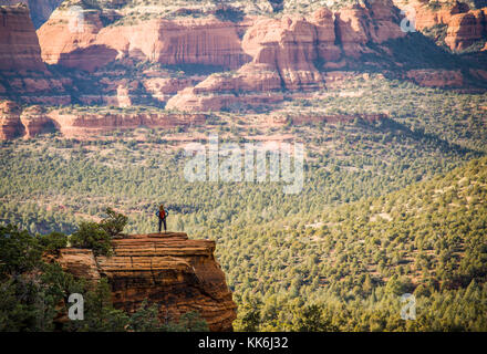 Une femme seule Randonneur au sommet d'un éperon rocheux dominant le Red Rock Canyon en dehors de Sedona, Arizona, USA. Banque D'Images