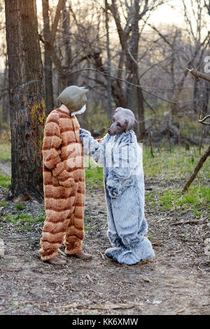 Deux personnes portant des costumes creepy chat et chien debout contre des arbres en forêt Banque D'Images