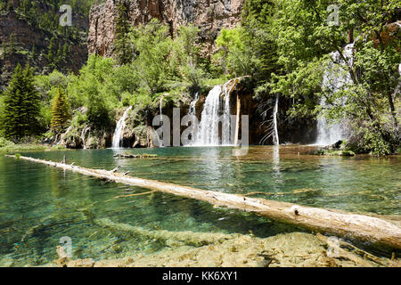 En cascade de l'eau de la rivière fraîche sur une barre rocheuse dans la végétation tropicale luxuriante dans un angle bas vue sur l'étang ci-dessous Banque D'Images