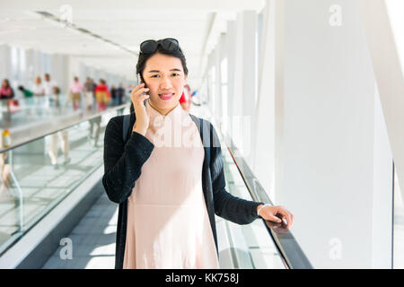 Fille à l'aide de téléphone alors que sur le tapis roulant à l'intérieur Banque D'Images