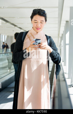 Fille à l'aide de téléphone alors que sur le tapis roulant à l'intérieur Banque D'Images