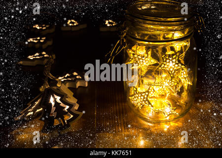 Lumières de Noël dans un pot sur la table en bois avec châssis de la neige Banque D'Images