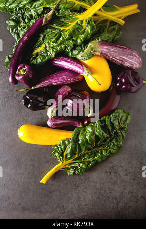 Petite aubergine, courgette jaune et violet, blettes poivre. arrière-plan foncé. La nourriture végétarienne du village Banque D'Images