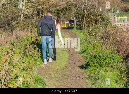 Jeune couple en train de marcher le long d'un halage boueux en essayant d'éviter la boue. Banque D'Images