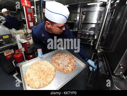 Dommage Controlman 1re classe Gary S Lee prépare pour la pizza et ailes nuit à bord du croiseur lance-missiles USS Vicksburg CG 69, Région du Golfe, 2012. Image courtoisie de spécialiste de la communication de masse 2e classe Nick C. Scott/US Navy. Banque D'Images