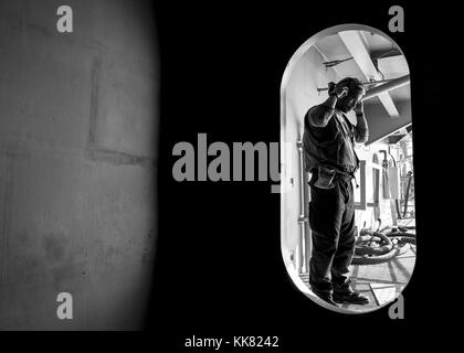 Technicien en électronique de l'aviation 3ème classe Xavier Smith, de Toscane, en Arizona, du VFA 102 e Escadron d'avions, met un casque en tissu à Assemblée générale avant d'entrer dans le poste de pilotage de la Marine américaine est que l'avant-déployé porte-avions USS Ronald Reagan CVN 76, dans les eaux situées au sud du Japon. Image courtoisie Mass Communication Specialist 3rd Class Ryan McFarlane/US Navy, 2015. Banque D'Images