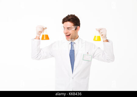 Portrait d'un jeune homme excité habillés en uniforme scientifique montrant les tubes de test isolé sur fond blanc Banque D'Images