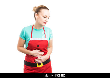 L'indigestion acide ou après le dîner de Noël concept avec femme portant un tablier rouge tenant son ventre en attente d'antiacide Banque D'Images