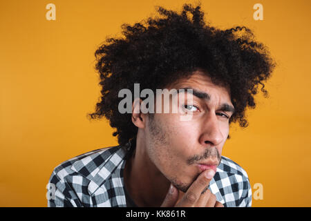 Portrait d'un drôle curieux african man looking at camera isolated sur fond orange Banque D'Images