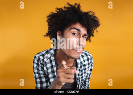 Portrait d'un jeune homme africain suspectes à un doigt pointé sur fond orange isolé de l'appareil photo Banque D'Images