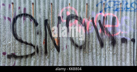 Détail de l'ondulée sale neige pulvérisée avec lettrage. D'ondulée clôture urbaine à partir de feuilles métalliques avec noir, rose et bleu par écrit. Des graffitis. Banque D'Images