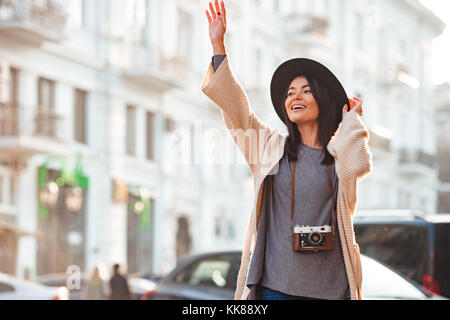 Belle asiatique woman in black hat catching taxi on city street Banque D'Images