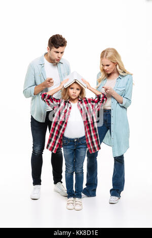 Portrait d'une famille d'avoir et de l'argumentation avec un enfant debout et tenant un livre isolé sur fond blanc Banque D'Images