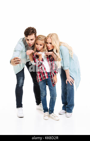 Portrait d'une belle jeune famille avec un enfant debout ensemble et prendre un isolé sur fond blanc selfies Banque D'Images