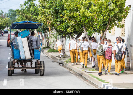 Les élèves à l'école à pied par berside un cheval transport déménagement possessions, Cienfuegos, Cuba Banque D'Images