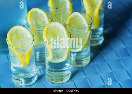 Verre de vodka et citron sur la surface bleue Banque D'Images