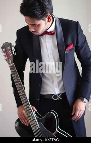 Man in tuxedo tenant une guitare, le profil avant. Banque D'Images