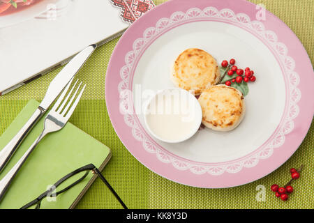 Petit déjeuner aux fruits rouges sur la plaque avec des adresses et verres et couverts sur une nappe verte Banque D'Images