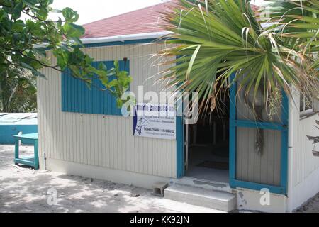 Une photographie de l'extérieur de la Middle Caicos Co-Op, le bâtiment en bois est peint en blanc et en bleu sur l'accentués des fenêtres et des portes, des palmiers peut être vu dans l'avant-plan et arrière-plan, le magasin représente des artistes locaux qui produisent des souvenirs pour les touristes, les îles Turques et Caïques, 2013. Banque D'Images